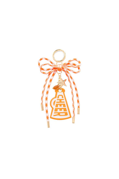 An orange and white striped bakers twine bow charm with a small gold-tone ring at the top, a tiny star charm, and an orange bell-shaped charm with a gold Chinese double happiness symbol, set against a plain white background.