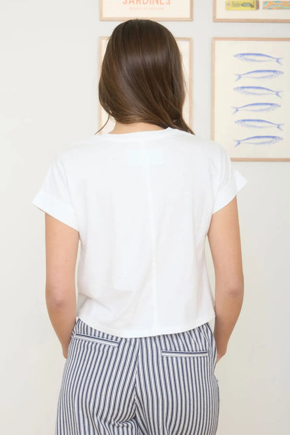 Person wearing a white t-shirt and striped pants standing in front of a wall with framed artwork.