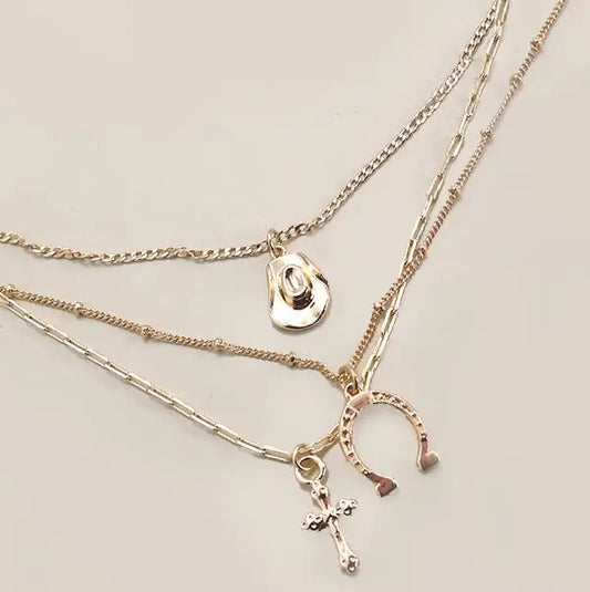 Three gold necklaces with various charms on a light gray background
