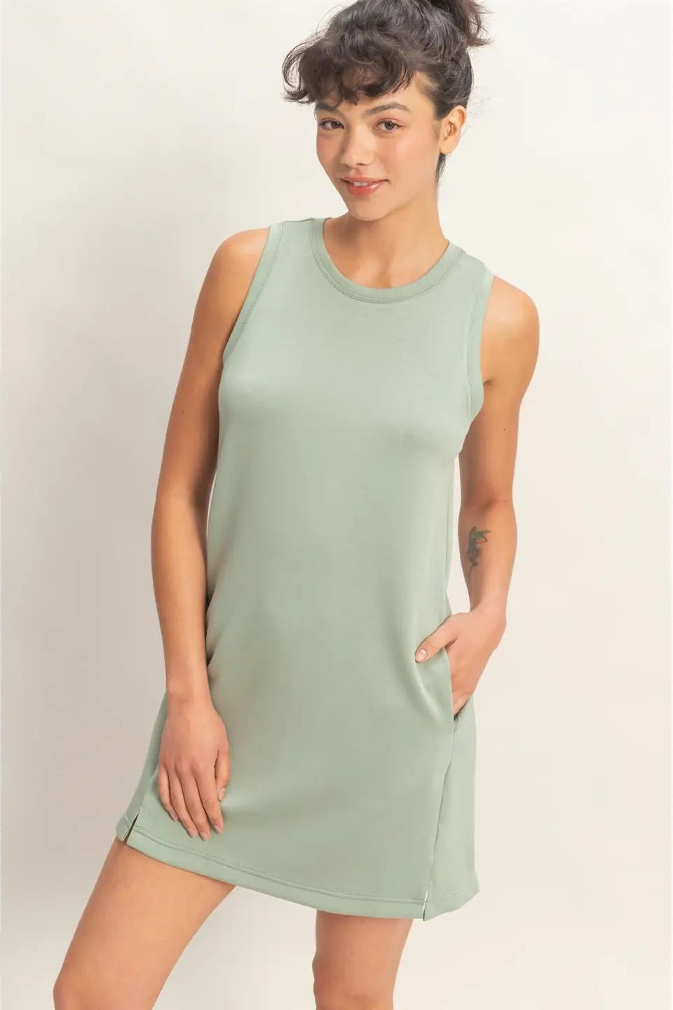 Woman wearing a light green sleeveless dress against a plain background