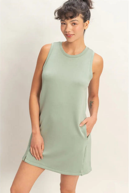 Woman wearing a light green sleeveless dress against a plain background