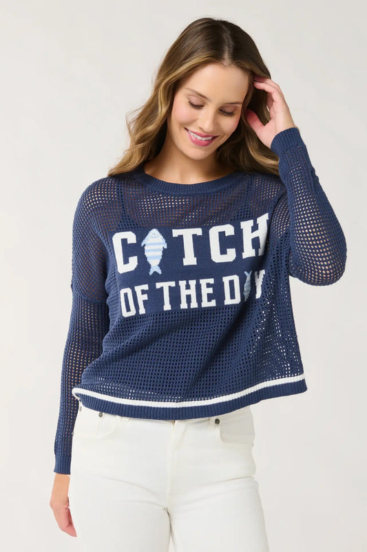 Woman wearing a navy blue mesh sweater with 'Catch of the Day' text and fish graphic on a white background