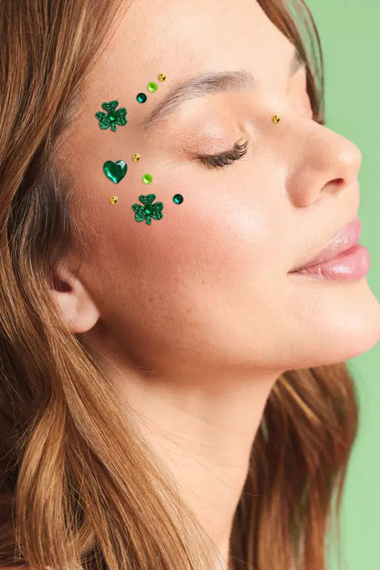 Close-up of a woman's face with decorative green gemstones on her cheek against a green background