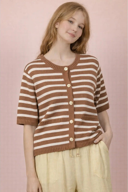 Young girl wearing a brown and white striped sweater against a pink background