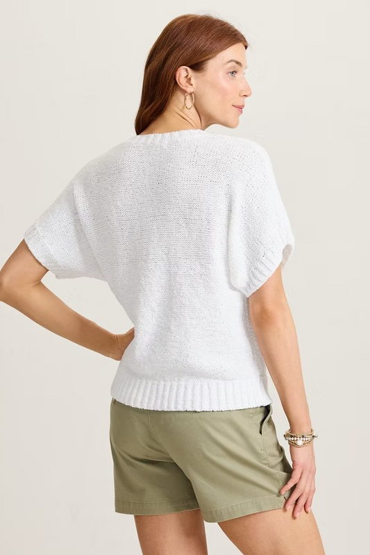 Woman wearing a white sweater and green shorts against a plain background