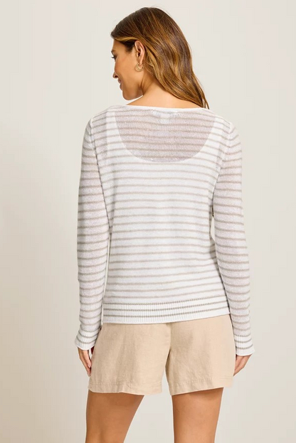 Woman wearing a striped long-sleeve top and beige shorts on a plain background