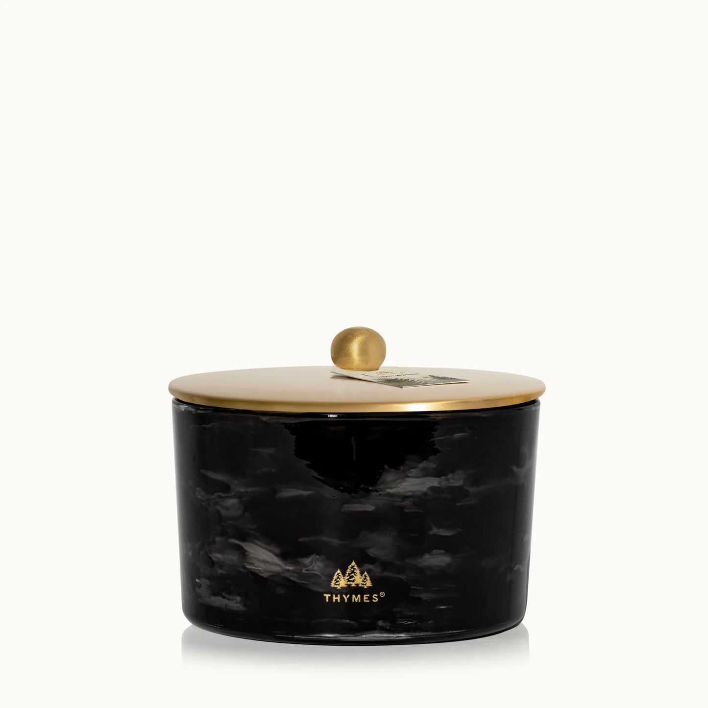 Black marbled candle jar with gold lid on a white background, featuring the Thymes logo.