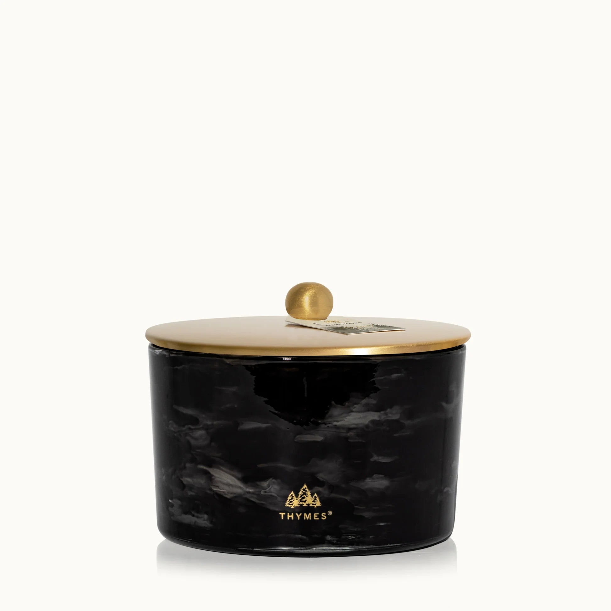 Black marbled candle jar with gold lid on a white background, featuring the Thymes logo.