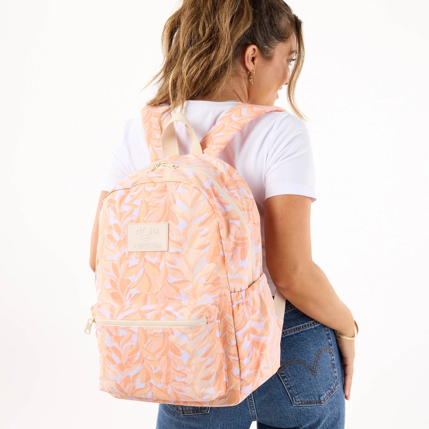 Person wearing a peach backpack with a white background