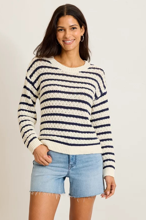 Woman wearing a striped sweater and denim shorts on a plain background