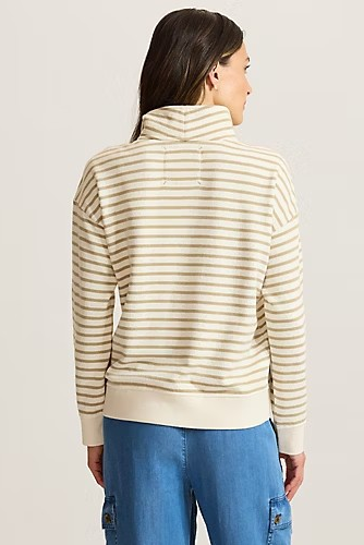 A woman shown from the back wearing a cream and tan striped mock neck sweatshirt and blue jeans against a light gray studio background.