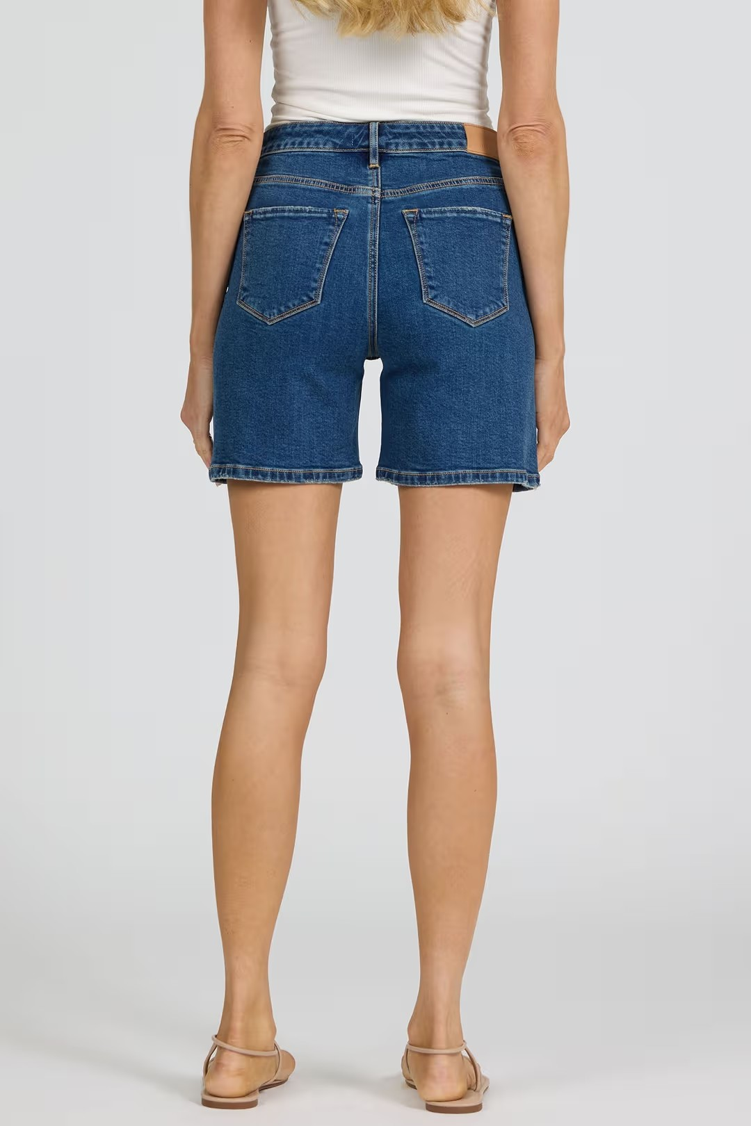 Person wearing blue denim shorts on a plain background