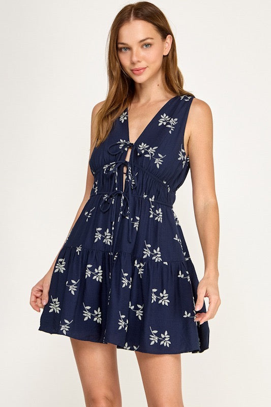 Woman wearing a navy blue dress with white floral pattern on a white background