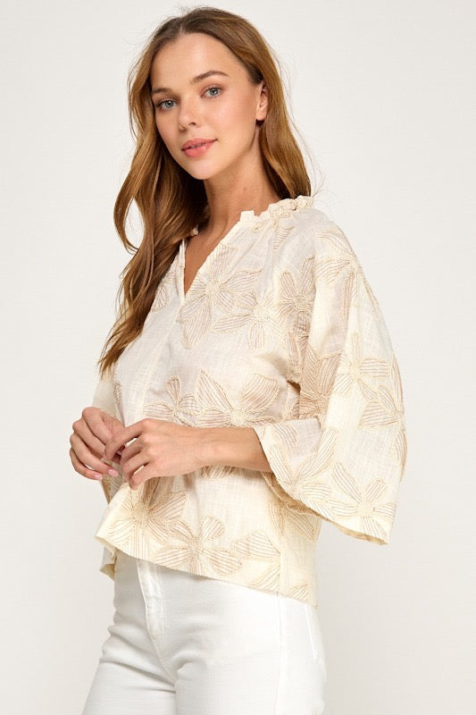 Woman wearing a light-colored blouse with a subtle pattern on a white background