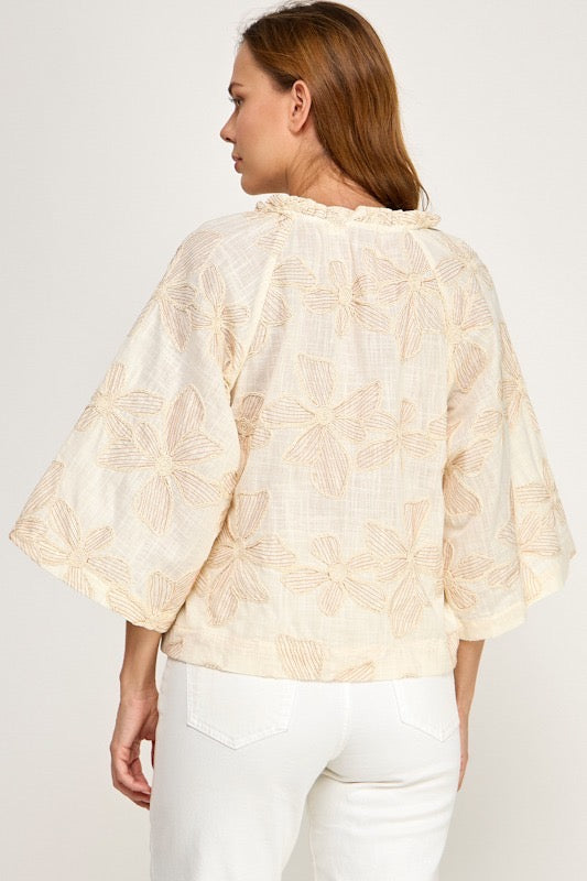 Woman wearing a light-colored floral blouse against a white background