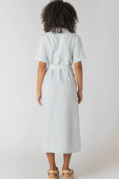 Person wearing a light blue dress with a belt on a white background