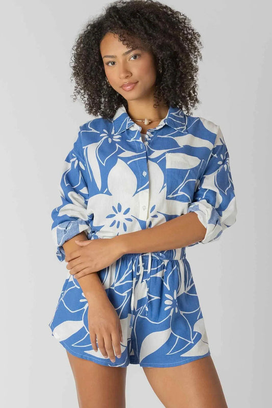 Woman wearing a blue and white floral romper on a gray background