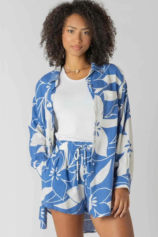 Woman wearing a blue floral kimono over a white shirt on a gray background