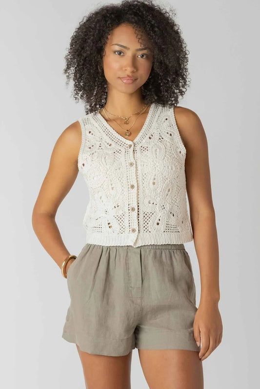 Woman wearing a sleeveless lace top and shorts on a plain background