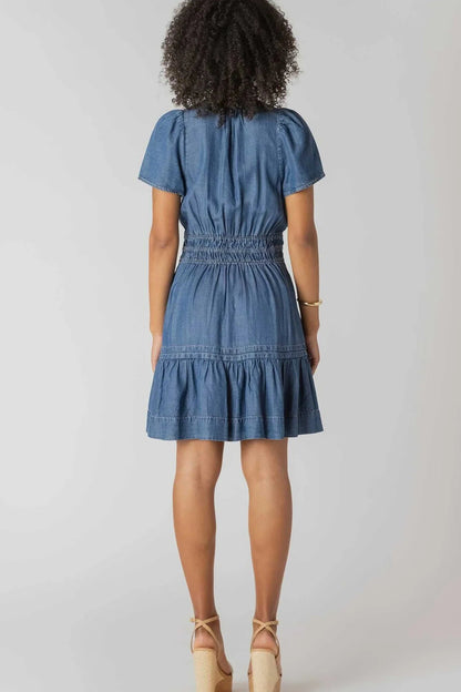 Woman wearing a blue denim dress on a plain background