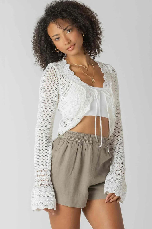 woman wearing crochet cardigan with tan shorts