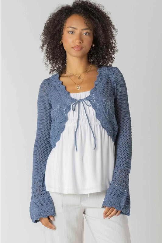 woman wearing crochet cardigan with white pants