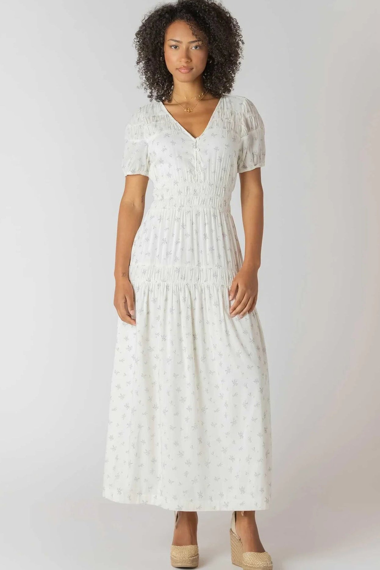 Woman wearing a white dress with a subtle pattern on a plain background