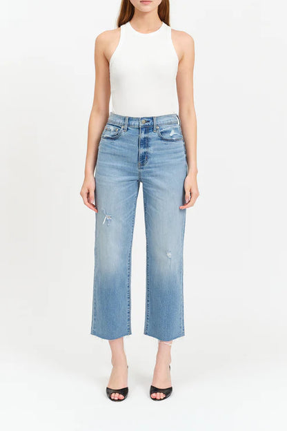 Person wearing light blue jeans and a white top on a white background