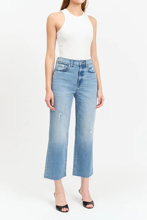 Person wearing light blue jeans and a white top on a white background