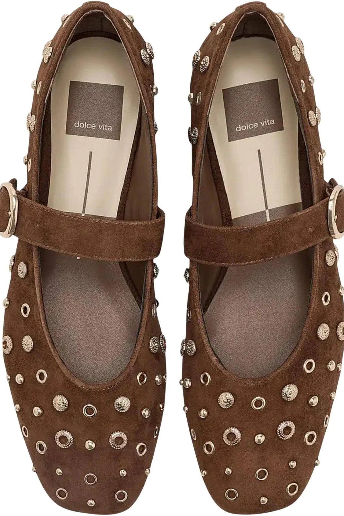 A pair of Dolce Vita brown suede Mary Jane shoes decorated with silver-tone metal studs and rings, shown from a top-down view on a white background.