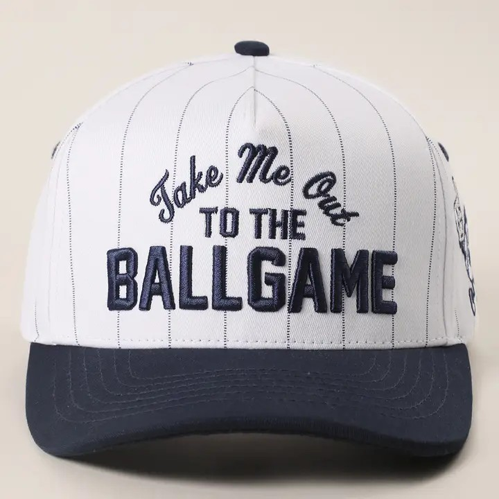 Baseball cap with 'Take Me Out to the Ballgame' text on a beige background