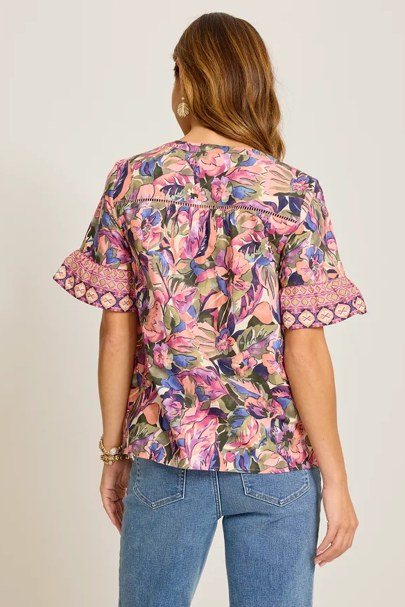 Woman wearing a colorful floral blouse with short sleeves on a plain background