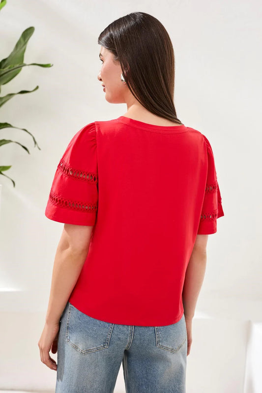 Woman wearing a red blouse with lace details on sleeves against a white background