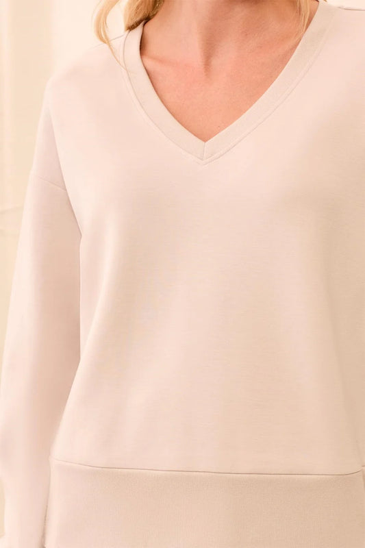 Beige sweater worn by a person, focusing on the neckline and shoulder area.