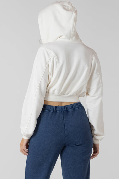 Person wearing a white hoodie and blue pants on a plain background