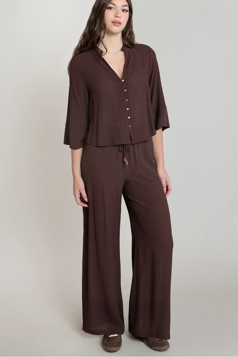 Woman wearing a brown jumpsuit on a plain background