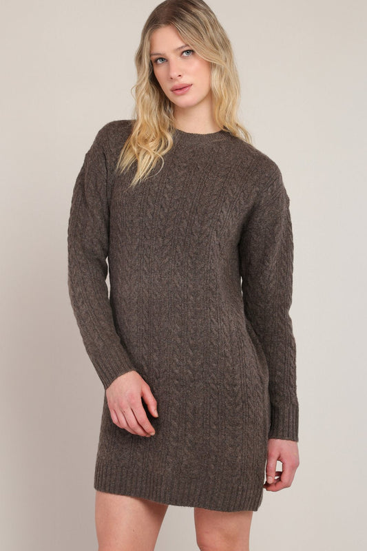 Woman wearing a brown knitted dress against a plain background