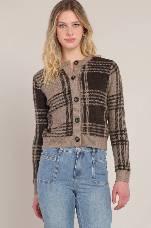 Woman wearing a plaid cardigan and jeans on a plain background