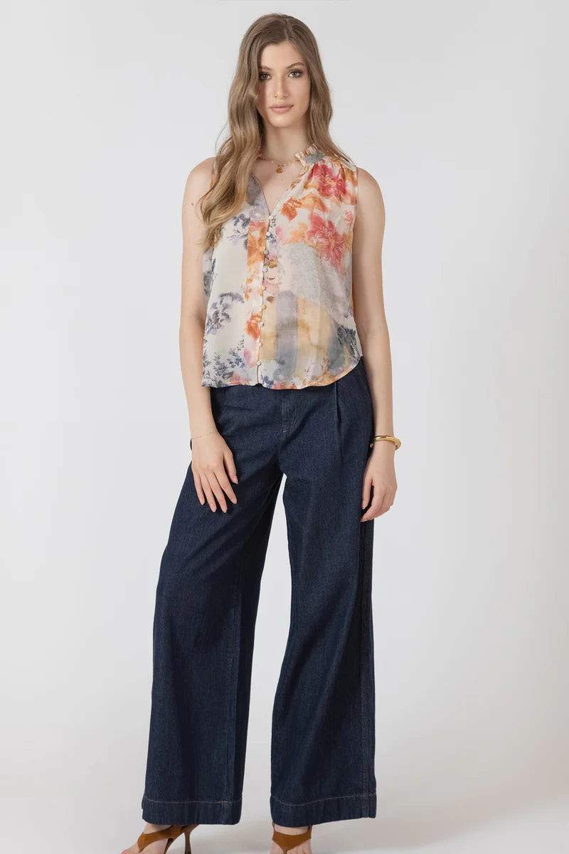 Woman wearing a floral sleeveless top and navy pants on a white background
