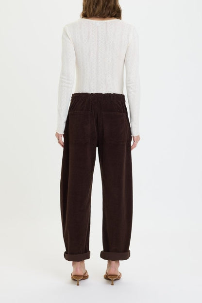 Person wearing brown pants and a white sweater on a white background