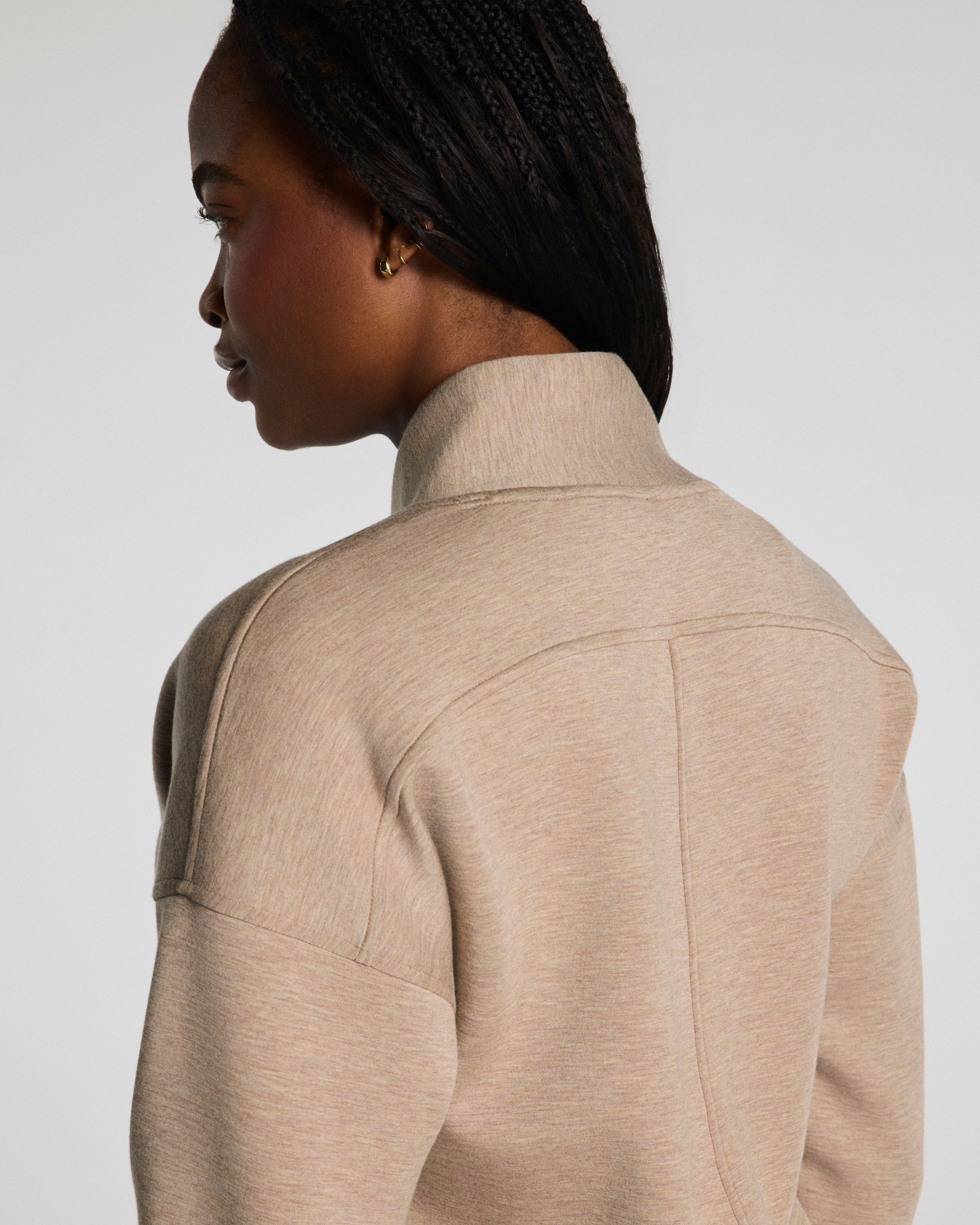 Person wearing a beige jacket on a plain background
