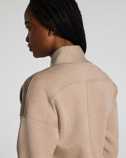 Person wearing a beige jacket on a plain background