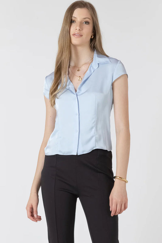 Woman wearing a light blue short-sleeve blouse and black pants on a white background