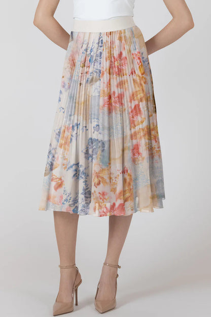 Woman wearing a colorful floral skirt with a white top on a plain background