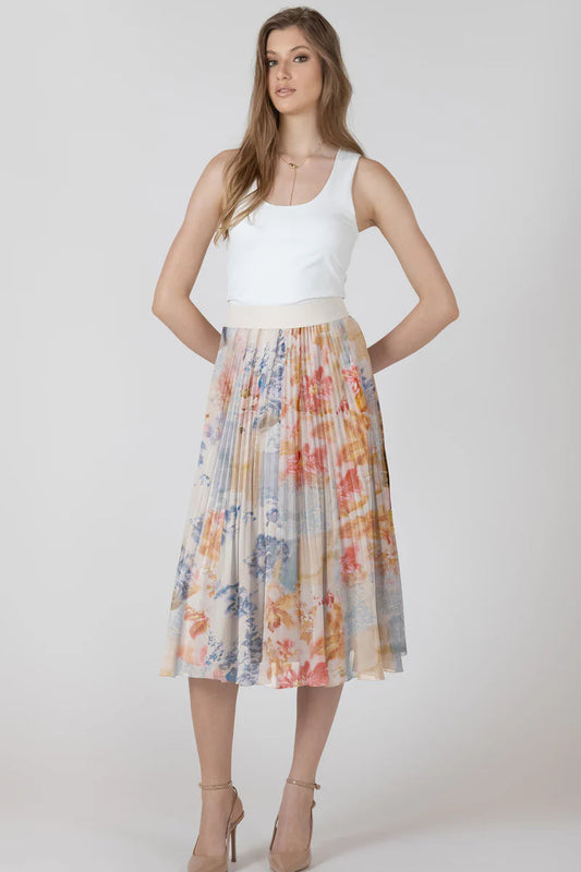 Woman wearing a white top and colorful pleated skirt on a plain background