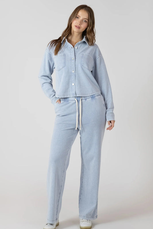 Woman wearing a light blue denim outfit on a plain background