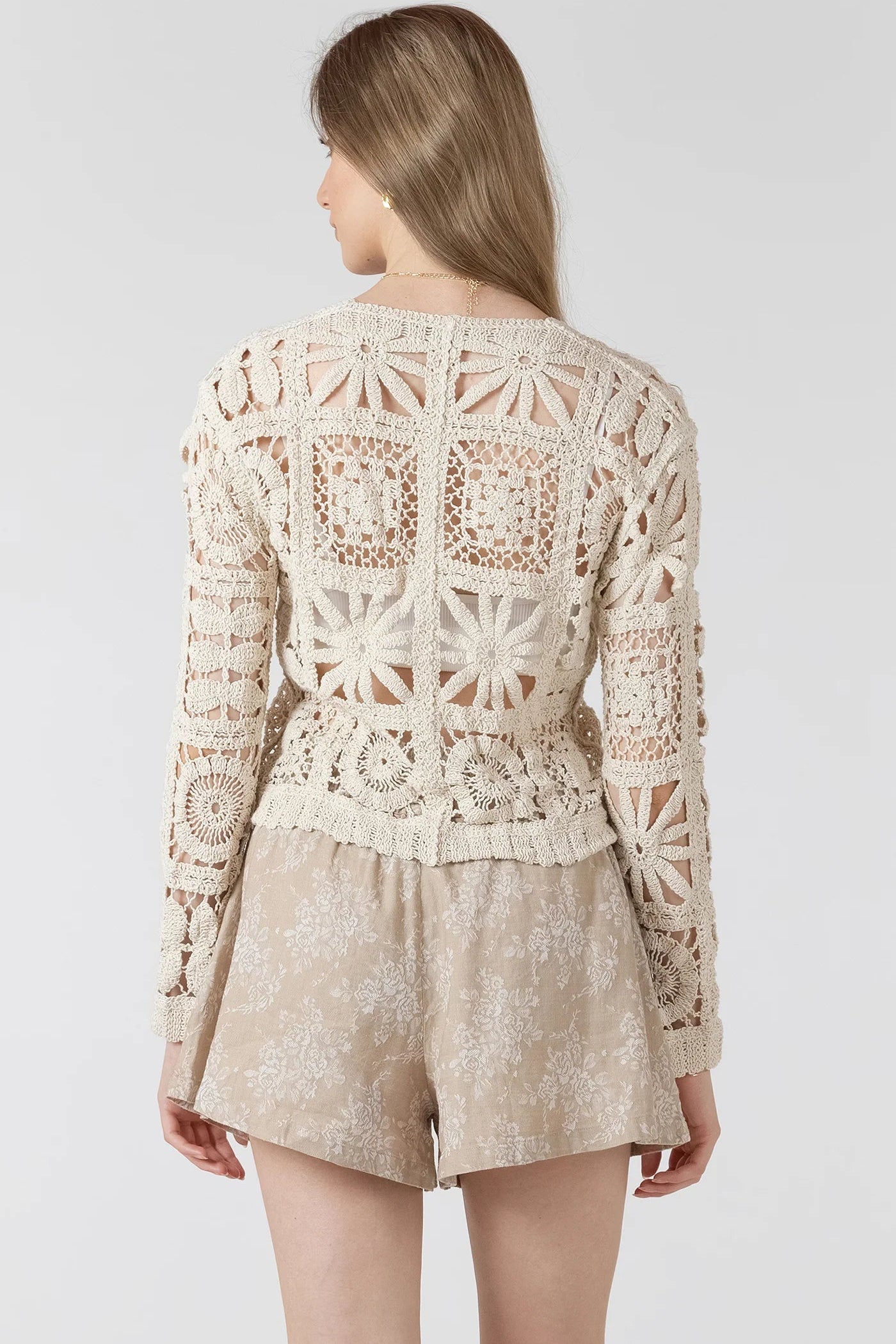 woman wearing crochet cardigan with tan shorts