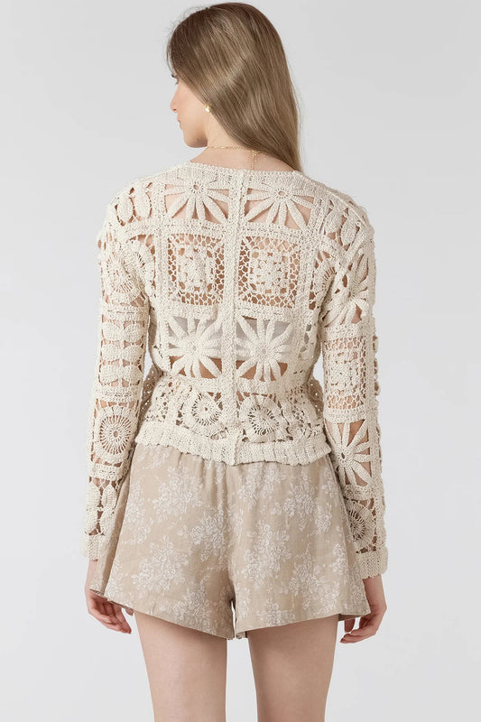 woman wearing crochet cardigan with tan shorts
