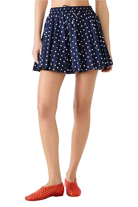 Navy blue polka dot skirt worn by a person on a white background