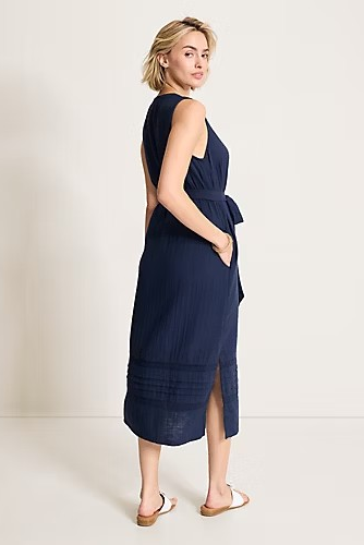 Woman wearing a navy blue dress with cut-out back on a plain background